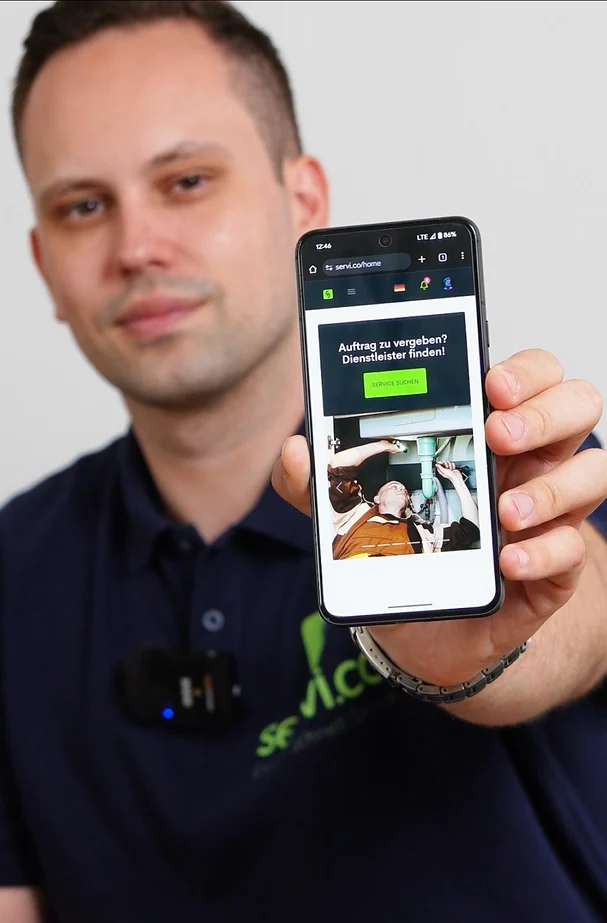 Provider in a navy milles polo holding a phone showing the milles mobile home.